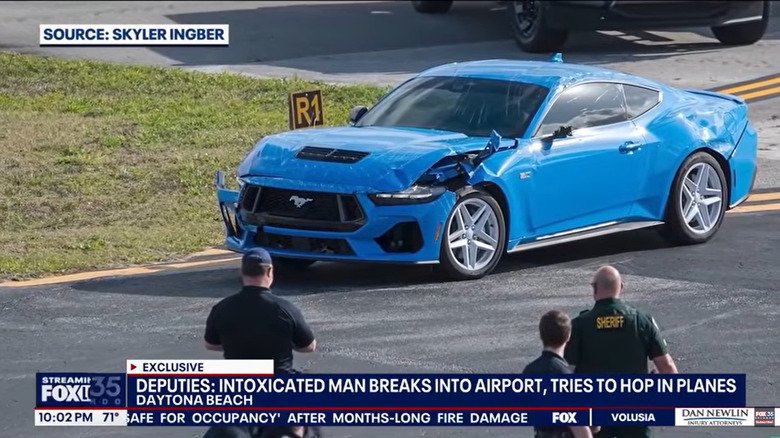 a screenshot from the fox news broadcast showing a close-up of the smashed blue S650 Mustang Parker used to break onto the DAB runway