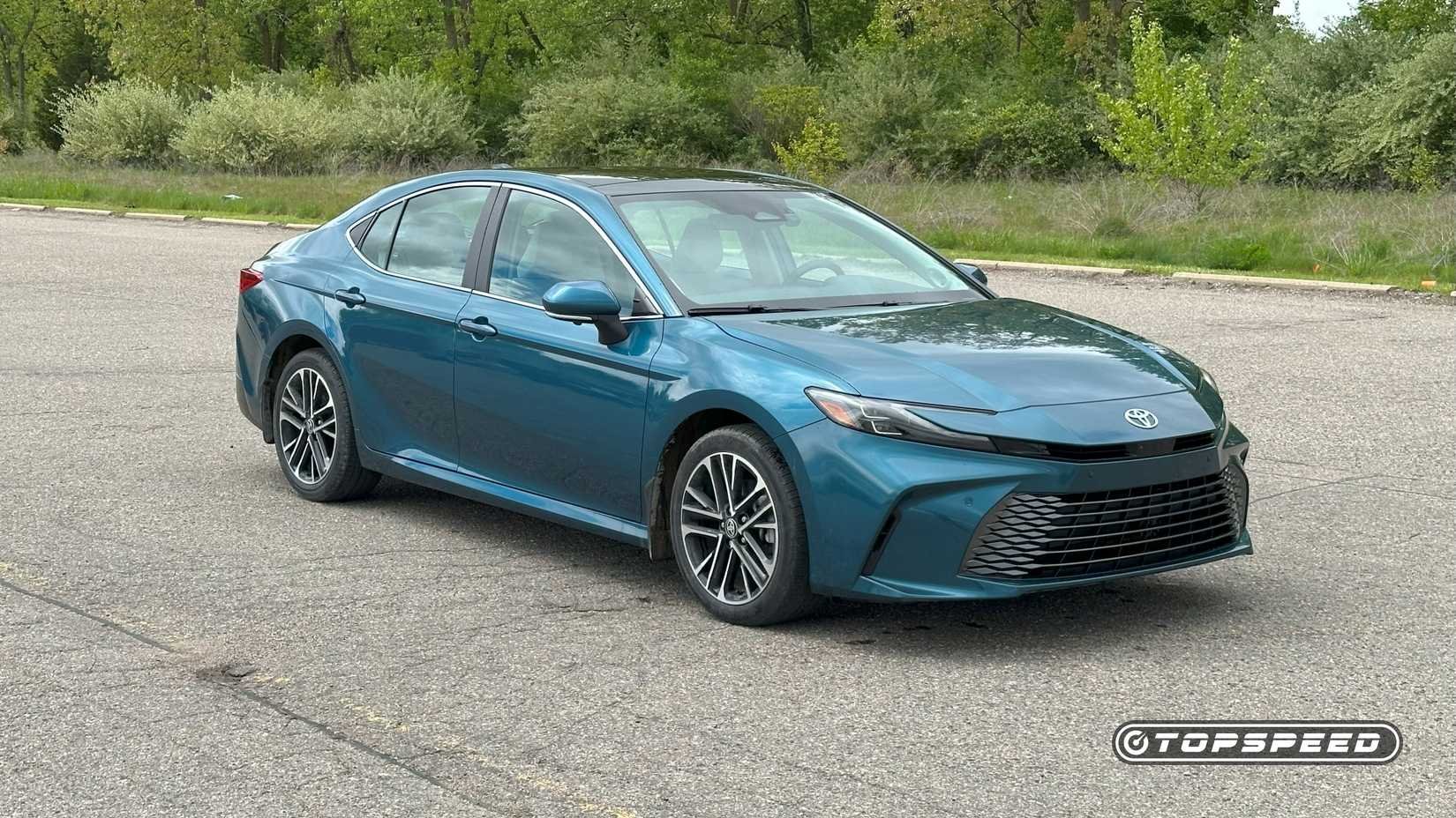 Front 3/4 shot of a blue 2025 [Toyota Camry](/article/toyota-camry-2024-fiabilite-consommation-et-guide-d-achat-complet) XLE AWD parked in front of trees
