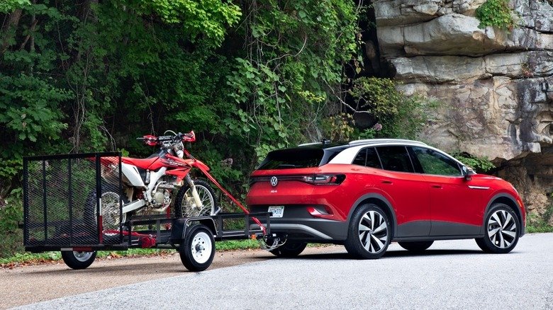 A red 2021 VW ID.4 AWD Pro S with the Gradient Package towing a motorcycle on a small trailer